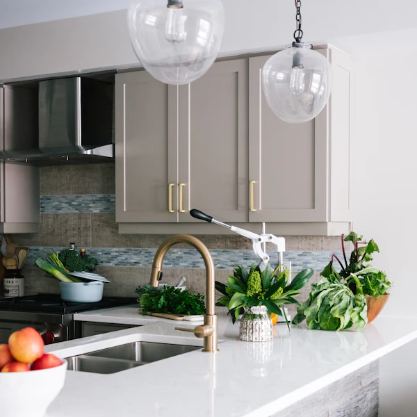 Marble kitchen counter with a brushed brass tap and fresh herbs