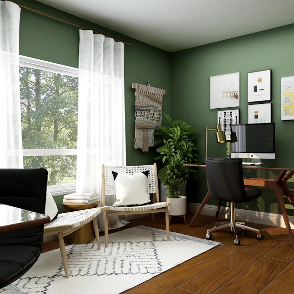 Home study with an olive green wall, wooden desk and framed art
