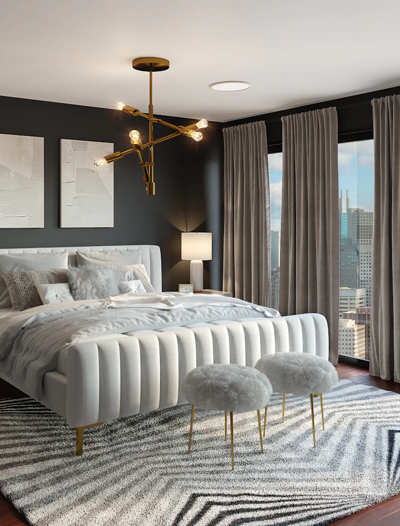 Master bedroom with a channel-tufted headboard, charcoal accent wall and sculptural brass chandelier