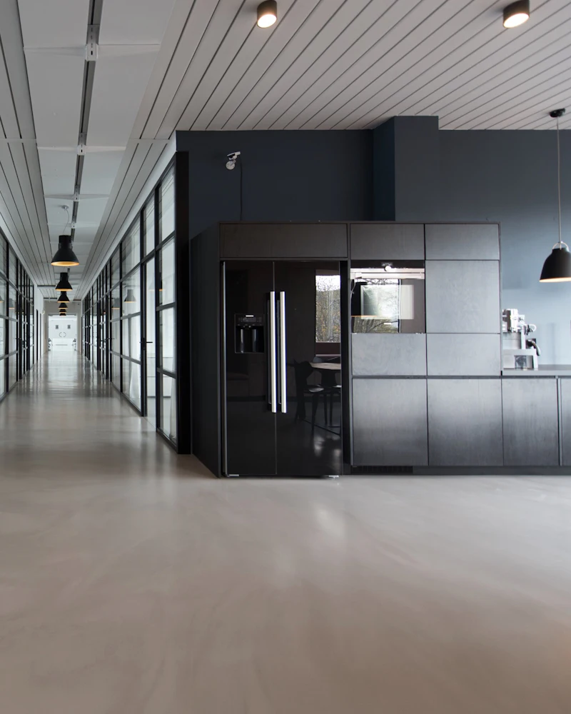 Corporate office corridor with glass cabins, a dark feature wall and polished concrete floor